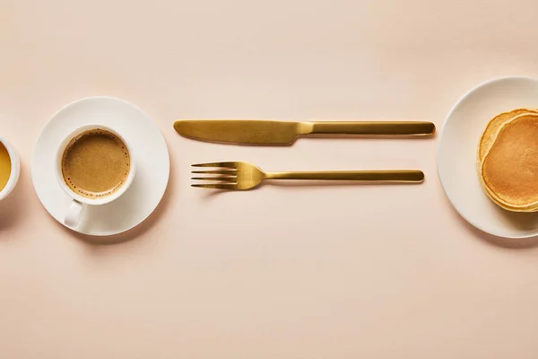 ピンクの金色のフォークとナイフの近くに泡とコーヒーのカップのトップビュー — ストック写真
