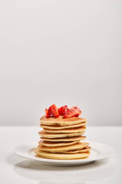 pancakes for breakfast with strawberries on white plate isolated on grey clipart