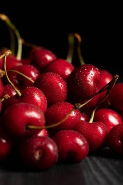 selective focus of red delicious and ripe cherries with water drops isolated on black clipart