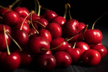 selective focus of red ripe cherries with water drops isolated on black clipart