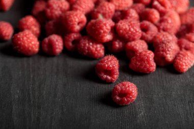 selective focus of tasty ripe raspberries scattered on wooden table clipart
