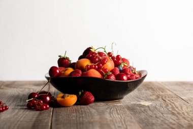 plate with mixed delicious ripe berries on wooden table isolated on white clipart