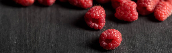 selective focus of delicious ripe raspberries scattered on wooden table, panoramic shot 