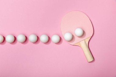 düz pembe arka plan üzerinde beyaz masa tenis topları ve raket ile yatıyordu
