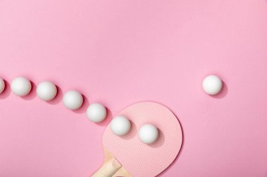 düz pembe arka plan üzerinde beyaz plastik masa tenis topları ve raket ile yatıyordu