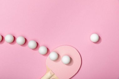 flat lay with white plastic table tennis balls and racket on pink background clipart