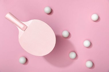 pembe arka plan üzerinde raket altında dağınık beyaz masa tenis topları üst görünümü