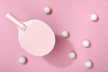 top view of white table tennis balls scattered under racket on pink background clipart