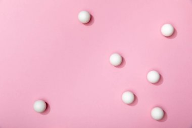 pembe arka plan üzerine dağılmış beyaz masa tenis topları üst görünümü