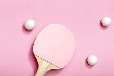 top view of white table tennis balls scattered near pink racket on pink background clipart