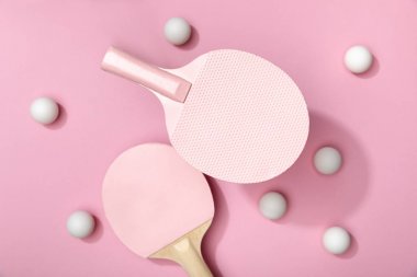 top view of white table tennis balls and rackets on pink background clipart
