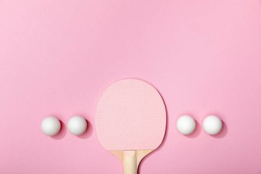 düz beyaz masa tenis topları ve pembe arka plan üzerinde ahşap raket ile yatıyordu