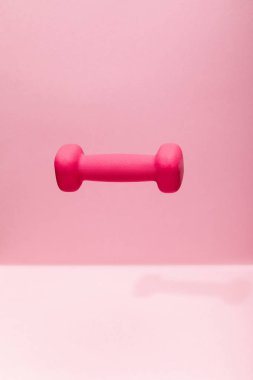 pink bright dumbbell levitating in air on pink background clipart