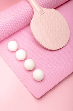 Pembe arka planda beyaz pinpon topları ve fitness minderinde raket