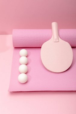 düz pembe arka plan üzerinde fitness mat üzerinde beyaz ping-pong topları ve raket ile yatıyordu