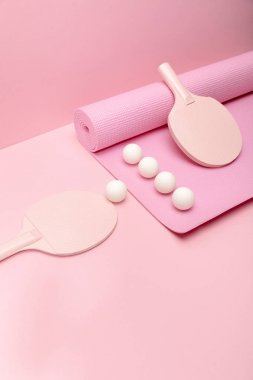white ping-pong balls and rackets on fitness mat on pink background