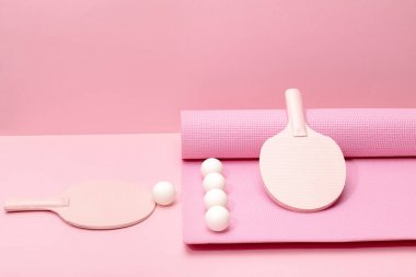 white ping-pong balls and pink rackets on fitness mat on pink background