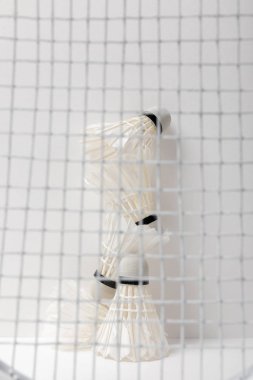 Beyaz badminton mekik horozları beyaz arka planda raket ağının arkasında
