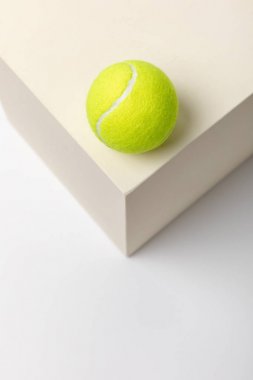 bright yellow tennis ball on cube on white background clipart