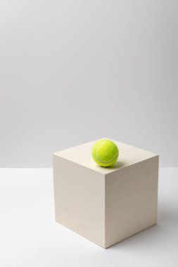 beyaz arka plan üzerinde kare küp üzerinde parlak sarı tenis topu