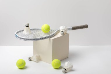 tenis raket ve beyaz arka plan üzerinde küp üzerinde shuttlecocks ile parlak sarı tenis topları