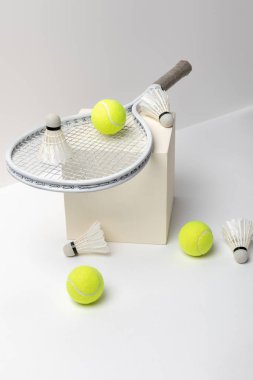 tenis raket ve beyaz arka plan üzerinde küp üzerinde shuttlecocks ile parlak sarı tenis topları