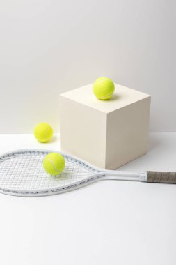 beyaz arka planda küp tenis raket ve parlak sarı tenis topları