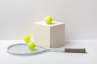beyaz arka planda küp tenis raket ve parlak sarı tenis topları