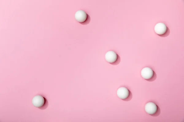 ピンクの背景に散らばった白い卓球のトップビュー — ストック写真