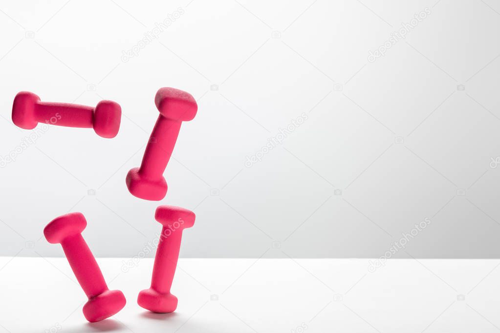 pink bright dumbbells flying in air on white background with copy space