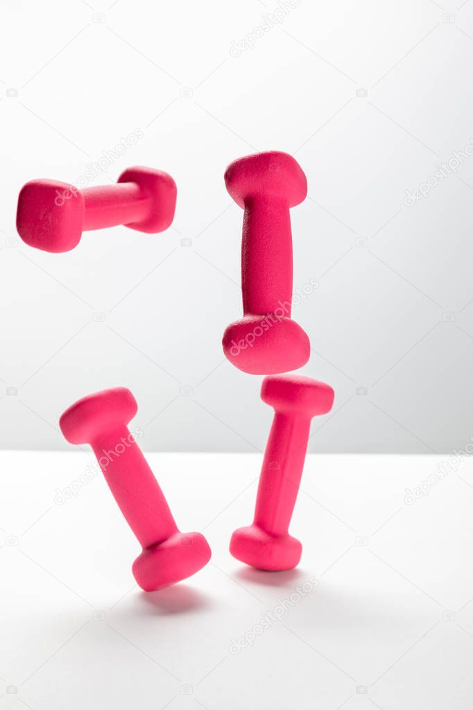 pink bright dumbbells flying in air on white background