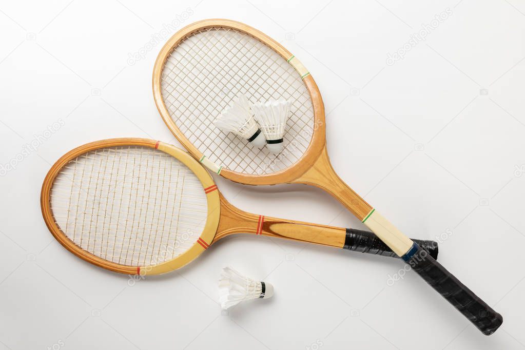 top view of wooden badminton rackets and shuttlecocks on white background