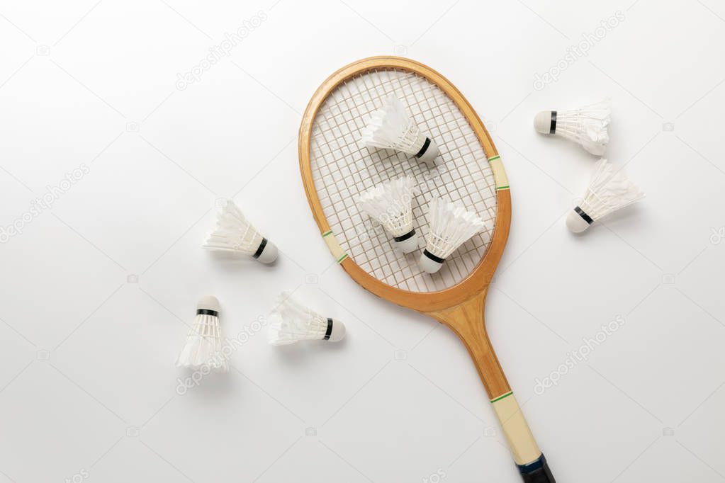 top view of wooden badminton racket and shuttlecocks on white background