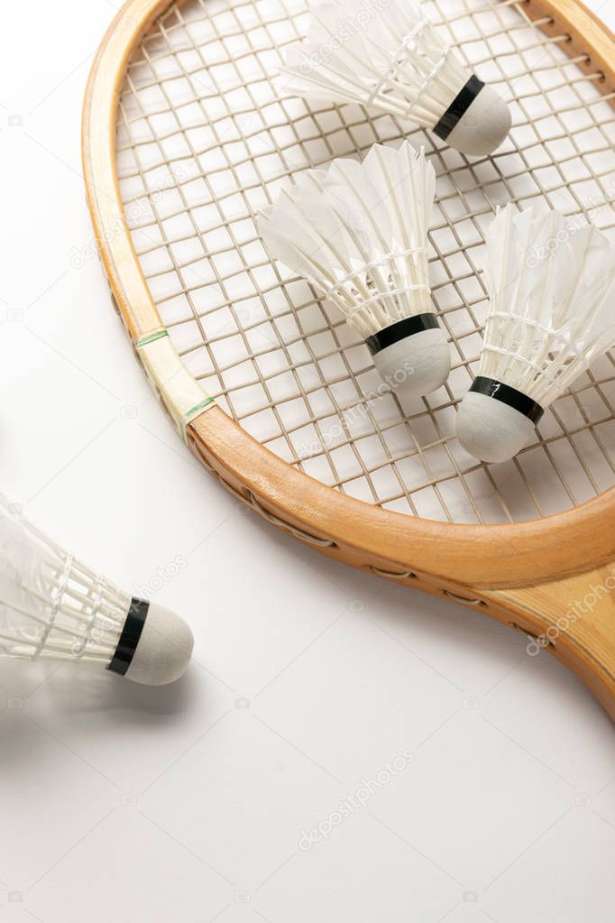 Close up view of wooden badminton racket and shuttlecocks on white background