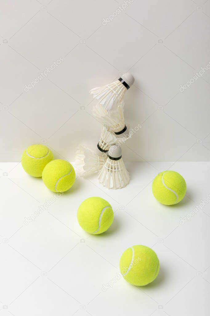 white badminton shuttlecocks and bright yellow tennis balls on white background