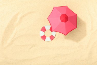 dokulu kum üzerinde lifebuoy ve pembe şemsiye ile kağıt plaj üst görünümü 