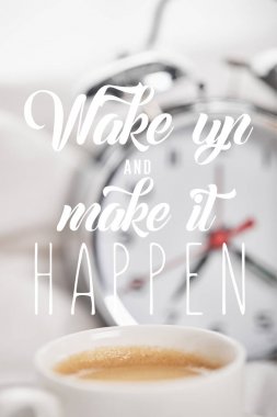 selective focus of coffee in white cup with silver alarm clock in bed on background with wake up and make it happen clipart