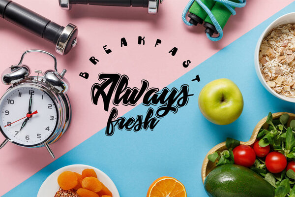 top view of delicious diet food and sport equipment with alarm clock on blue and pink background with breakfast always fresh lettering