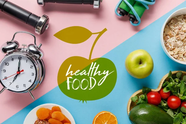 美味的饮食食品和运动器材的顶视图与闹钟的蓝色和粉红色背景与健康食品字母 — 图库照片