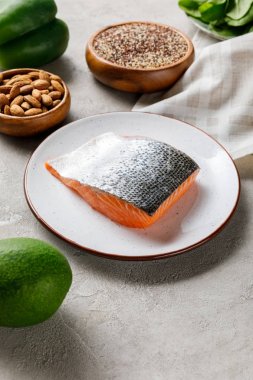 fındık ve avokado, ketojenik diyet menüsü yakınında beyaz plaka üzerinde taze çiğ somon