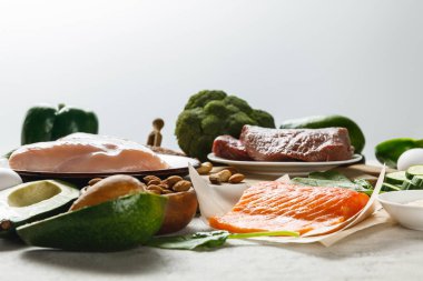 fresh raw salmon, meat and chicken breasts near green vegetables isolated on grey, ketogenic diet menu clipart