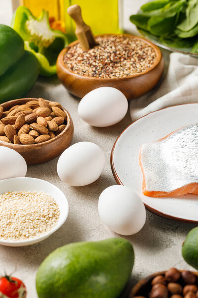 свежий сырой лосось на белой тарелке рядом с орехами, овощами и яйцами, кетогенное меню
