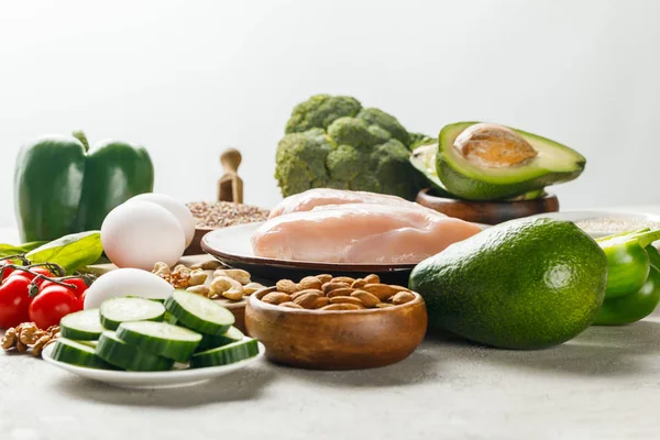 新鲜生鸡乳房附近的绿色蔬菜和坚果隔离在灰色 生酮饮食菜单 — 图库照片