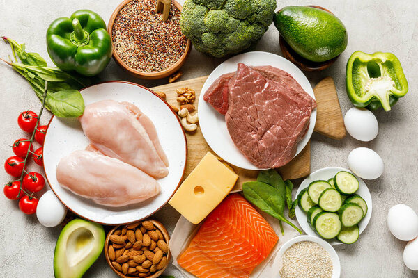 top view of raw fresh ketogenic diet ingredients on wooden chopping board on grey background with copy space