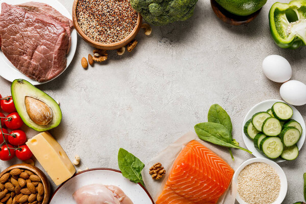 top view of raw salmon, chicken breasts and meat near nuts, dairy products and vegetables on grey background with copy space, keto diet menu