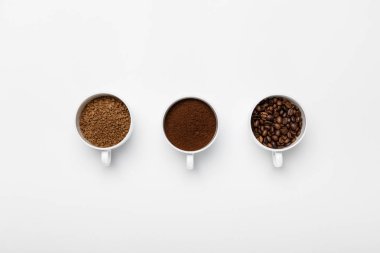 flat lay with three types of coffee grinding in cups on white background with copy space clipart