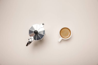 top view of metal coffee pot and delicious coffee in cup on beige background clipart