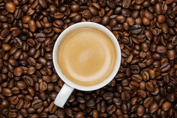 在新鲜咖啡颗粒上用白杯中美味的咖啡的顶视图 — 图库照片
