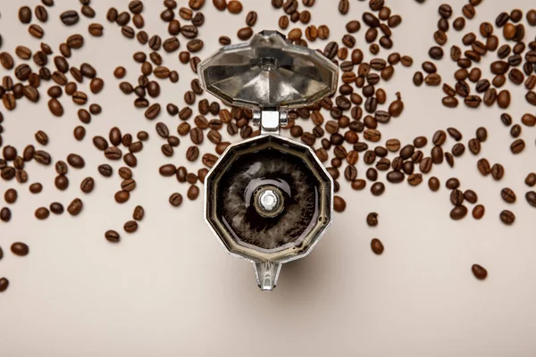打开的金属咖啡壶与新鲜咖啡豆附近的米色背景的顶视图 — 图库照片