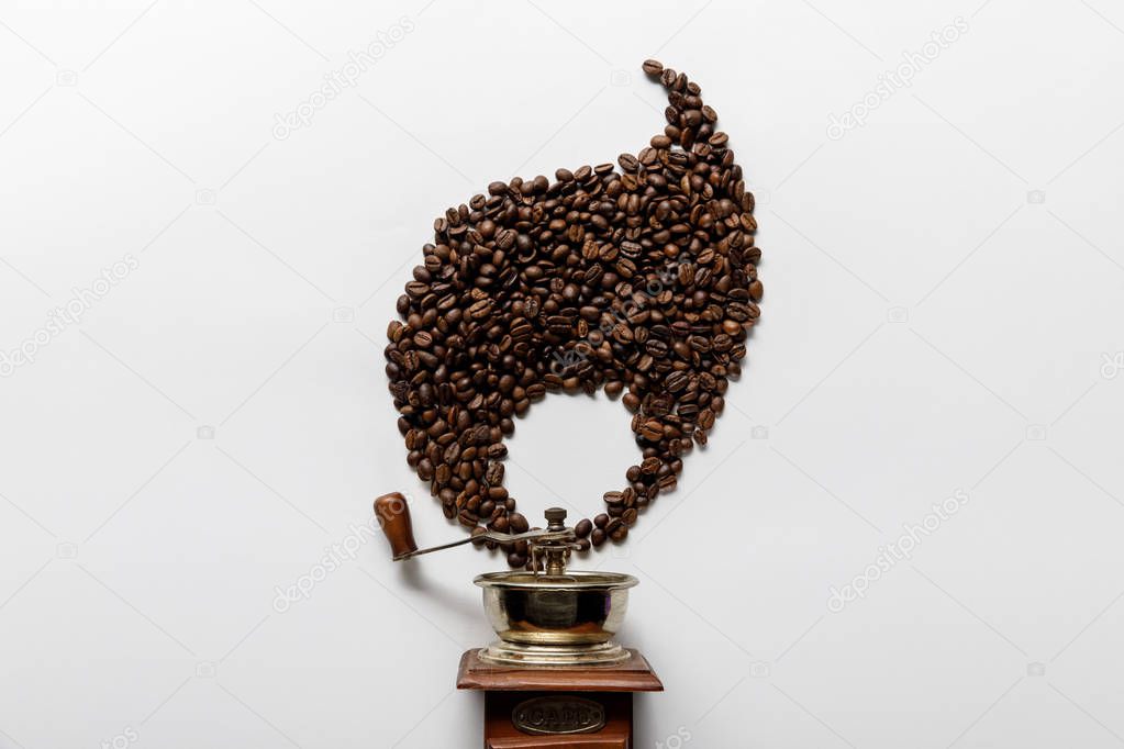 top view of vintage coffee grinder near flame made of coffee grains on white background